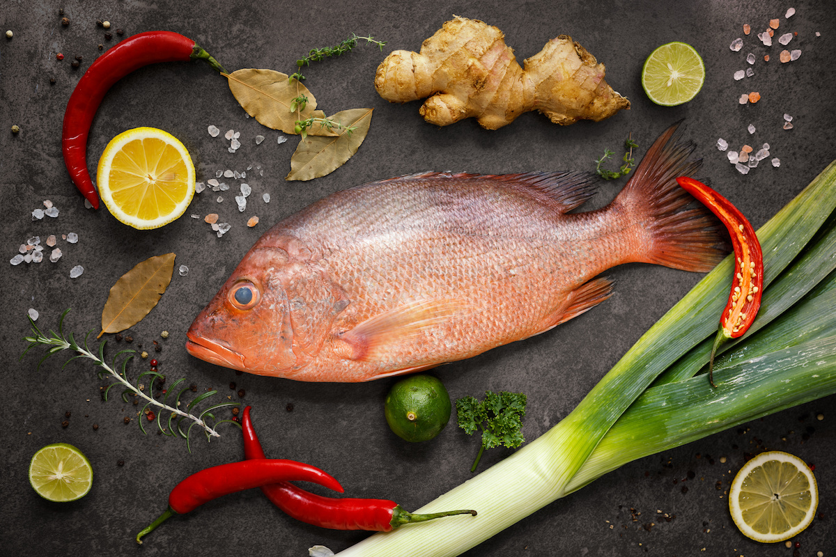 Peix parp vermell sobre fons negre amb ingredients